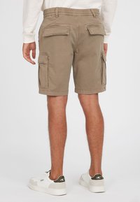 Khaaki cargo shorts yang terbuat dari katun dengan pinggang elastis, dilengkapi dengan dua saku samping dan dua saku belakang.