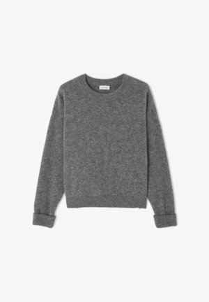 Pilkas vilnonis megztinis su apvalia iškirpte, ilgomis rankovėmis ir įvirintais rankogaliais. Minkšta tekstūra ir klasikinis, laisvas siluetas. Be matomų raštų ar akcentų.