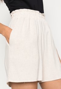 Jasno beżowe szorty z elastycznym pasem, z teksturowanej tkaniny, z bocznymi kieszeniami dla dodatkowej wygody.