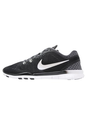 Chaussure de course Nike noire et grise avec logo swoosh blanc et semelle blanche flexible, vue de côté sur fond blanc.
