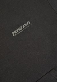 Czarna bluza z gładką fakturą, z szarym nadrukowanym logo, które mówi "jack & jones" oraz "CREATIVE DEPT." z przodu.