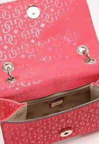 Růžová syntetická kabelka s logem, uzavíratelná na cvoček, se stříbrnými kovovými doplňky a béžovou podšívkou s logem.