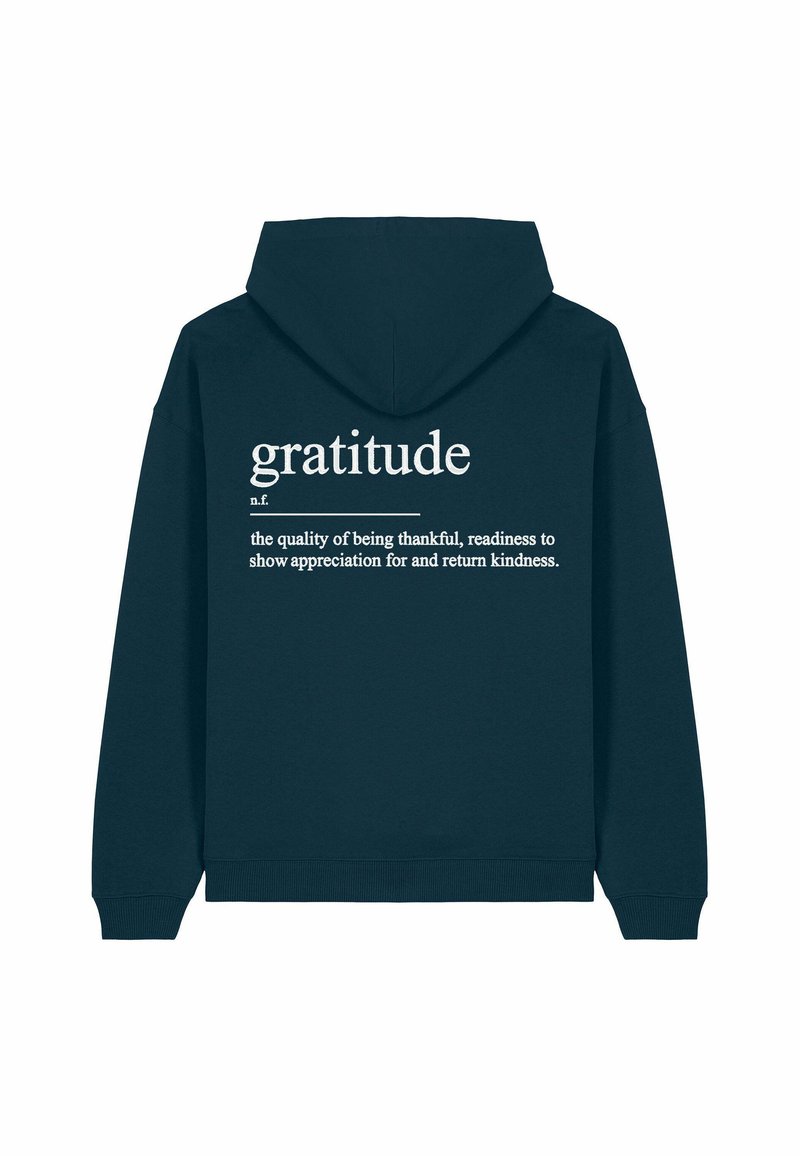 Sötétzöld kapucnis pulóver, hátul fehér szöveggel, amely a "hála" szót definiálja letisztult betűtípussal. Az anyag puha kinézetű, lazán illeszkedik.