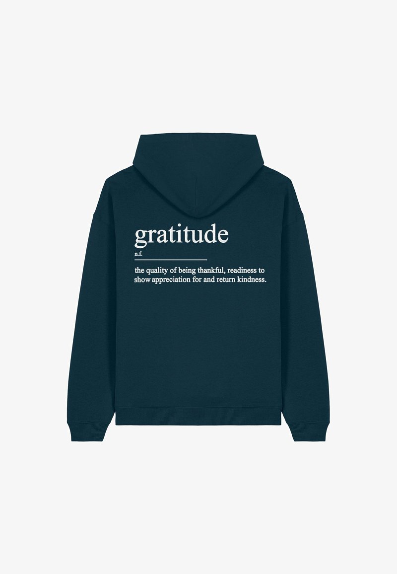 Sötétzöld kapucnis pulóver, hátul fehér szöveggel, amely a "hála" szót definiálja letisztult betűtípussal. Az anyag puha kinézetű, lazán illeszkedik.