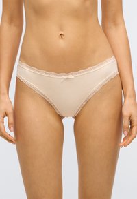 Culotte beige ornée de dentelle et d'un délicat nœud à l'avant, fabriquée en tissu doux et lisse avec une coupe ajustée.