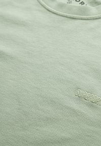 Mintgroen T-shirt gemaakt van zacht katoen, met een geribde ronde hals en subtiele "SUPERDRY" borduring rechtsonder.