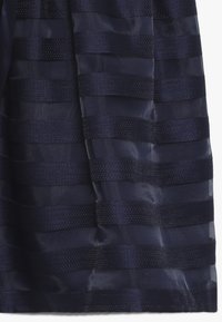 Tessuto blu scuro con strisce orizzontali alternate in tessuto testurizzato e trasparente, che mostrano pieghe e riflessi di luce.