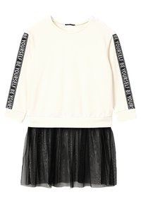 Top de algodón blanco con mangas de tres cuartos, que presenta cinta negra con la frase "SÉ TÚ MISMO" en las mangas y una falda inferior de tul negro.
