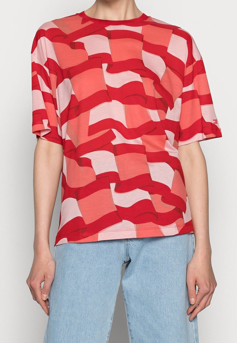 T-shirt à manches courtes rouge et rose avec un motif abstrait en damier, fabriqué en tissu léger avec un col rond.