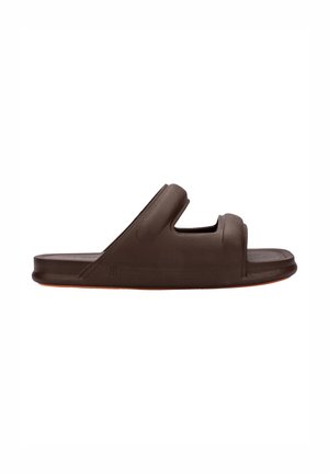 Sandale glissante marron en matériau lisse avec deux ouvertures découpées, présentant un design à large bande et une semelle légèrement surélevée.