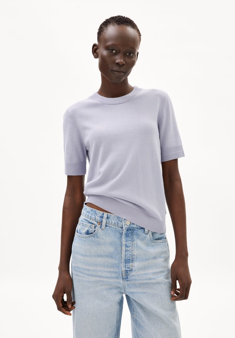 Lila gebreid sweater met korte mouwen en een geribbelde halslijn, gecombineerd met lichtblauwe hoge taille jeans met een ontspannen pasvorm en vervaagde textuur.