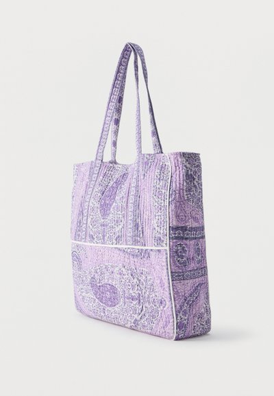 Sac fourre-tout matelassé lavande avec motifs cachemire, deux longues poignées et détails en passepoil blanc, debout sur un fond uni.