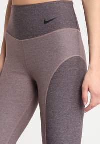 Legginsy z wysokim stanem w kolorze bordowym i szarym. Wykonane z elastycznej tkaniny o gładkiej strukturze, z czarnym logo i kontrastowymi szwami.