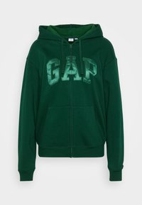 Vihreä huppari, jossa on GAP-logo vaaleammassa vihreässä, täysi vetoketju, suuret etutaskut ja kiristysnauha hupussa. Valmistettu pehmeästä, teksturoidusta kankaasta.