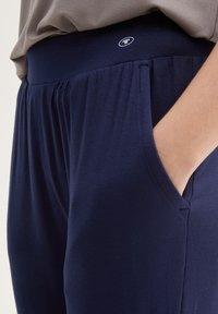 Joggers leggeri di colore blu navy, realizzati in tessuto leggero, con cinturino elastico, tasche laterali e dettagli arricciati in vita.