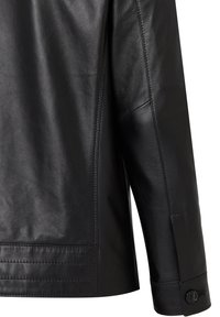 Zwarte leren jas met een soepele textuur, pasvorm op maat en een knoopsluiting op de manchetten. Inclusief gedetailleerde stiksels langs de naden.