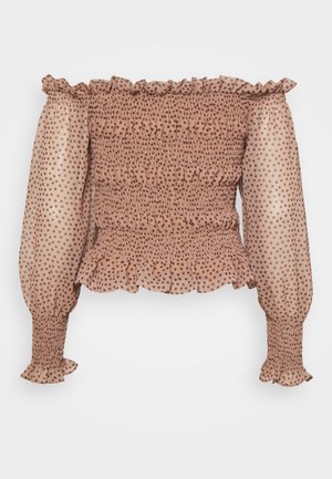 Off-shoulder beige bluse med brune polkaprikker, smocket krop, lange puffede ærmer og flæsekant ved halsudskæring, manchetter og kant.
