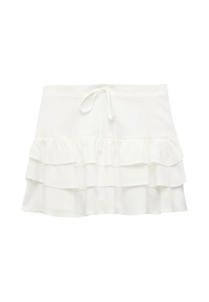 Jupon blanc à volants avec une taille élastique, comportant trois niveaux de volants, fabriqué en tissu doux au toucher lisse.