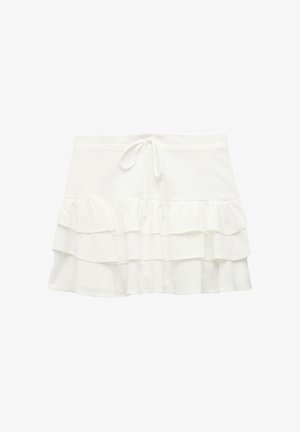 Jupon blanc à volants avec une taille élastique, comportant trois niveaux de volants, fabriqué en tissu doux au toucher lisse.