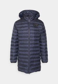 Marinblå pufferjacka med huva, med dragkedja framtill, kviltade sektioner och en synlig logopatch på bröstet. Lättviktig och isolerad design.