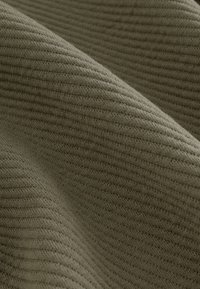 Tessuto ribbed khaki con una morbida consistenza, caratterizzato da strisce parallele e da un leggero lucido, che scende in pieghe morbide.
