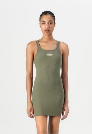 Olivgrünes, geripptes Tankkleid mit taillierter Silhouette, minimaler Markierung auf der Brust und dünnen Schulterträgern. Weiche Textur.