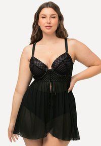 Zwarte lingerie-set met een geometrisch patroon bh en een doorschijnende, vloeiende rok. Inclusief verstelbare bandjes en een gestrikte taille detail.