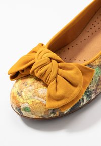 Żółte zamszowe baleriny z węzłem i teksturowanym, wielokolorowym noskiem przypominającym skórę węża. Wewnętrzna podszewka z perforacjami.