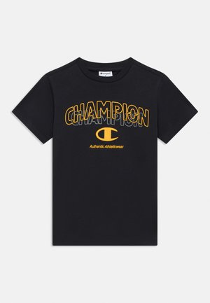 Fekete pamut póló, nagy sárga "CHAMPION" felirattal és alatta kis "Authentic Athleticwear" szöveggel, rövid ujjú, kerek nyakkivágással.
