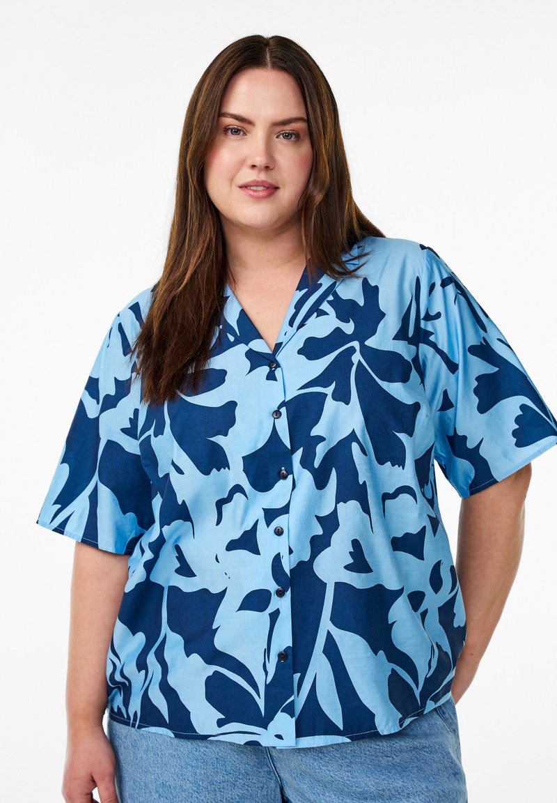 Camicia a maniche corte, con bottoni, di colore azzurro chiaro con motivo floreale blu scuro; realizzata in tessuto liscio con una vestibilità comoda e un design a V.