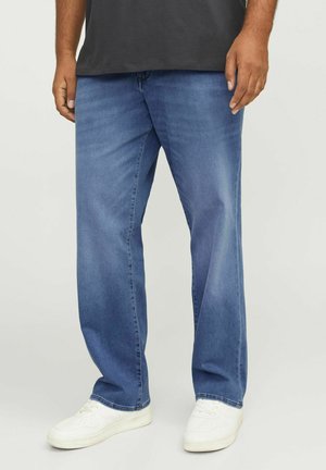 Blå denim jeans med en afslappet pasform, der har en let slidte finish, klassisk fem-lommer design, og båret med hvide sneakers.