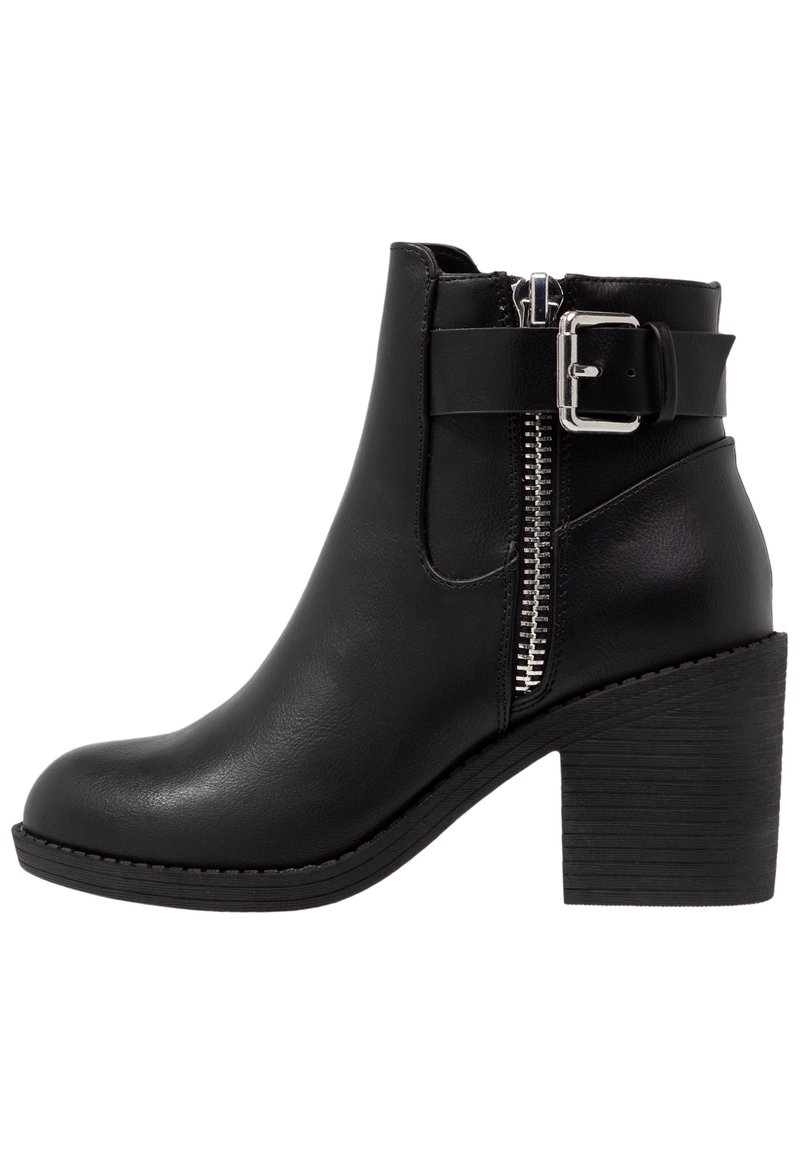 Bottine noire avec une texture en cuir lisse, fermeture éclair latérale, détail de boucle et talon empilé. Elle présente un bout arrondi et une semelle durable.