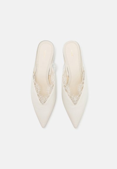Zapatos slingback de punta afilada en tejido blanco roto, con detalles de encaje en los bordes, forro texturizado y un acabado suave.