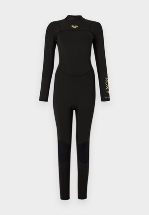 Combinaison noire intégrale avec manches longues, renforts aux genoux et logo jaune Roxy sur la poitrine et l’avant-bras gauche.
