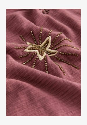 Tekstil z teksturirano, mauve tkanino, ki vsebuje zvezdni vzorec v bež niti, okrašen z majhnimi rjavimi biseri v radiacijskem vzorcu.