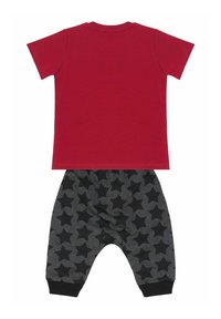 Rød kortærmet t-shirt parret med sorte bukser med stjernemønster. Bukserne har elastisk talje og manchetter ved anklerne.