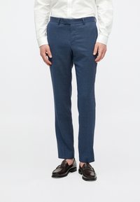 Pantaloni albaștri suitați cu o textură subtilă, croială ajustată, talie asortată și buzunare laterale, asortați cu mocasini maro închis.