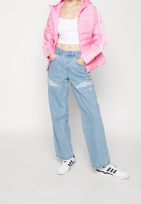 Vaaleanpunainen toppatakki valkoisilla raidoilla, lyhyt valkoinen paita, vaaleansiniset leveälahkeiset farkut korjausaidoilla ja valkoiset lenkkarit mustilla yksityiskohdilla.