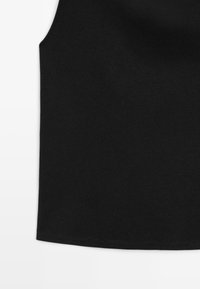 Zwart mouwloos geribd gebreid topje met een ronde hals en een rechte zoom op een witte achtergrond.