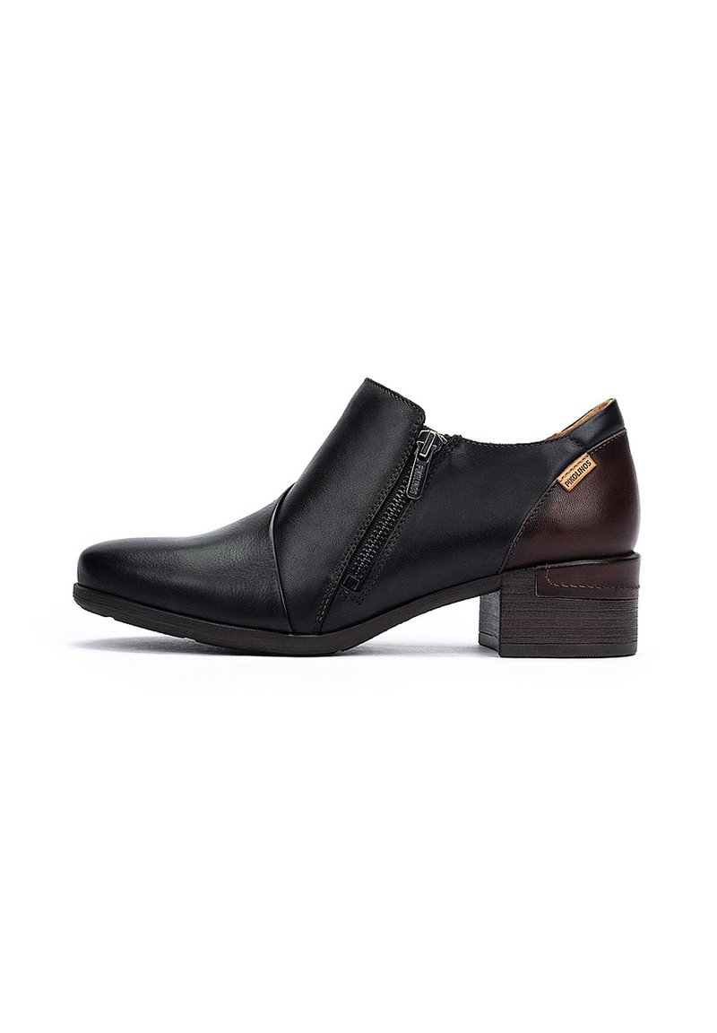 Stivaletti in pelle nera alla caviglia con zip laterale, caratterizzati da un dettaglio marrone sul tallone e un tacco basso a blocco. Texture liscia e design elegante.