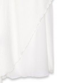 Biała odzież o teksturowanym, warstwowym wzorze z lekko asymetrycznym dołem. Lekki materiał sprawia, że całość wygląda zwiewnie.