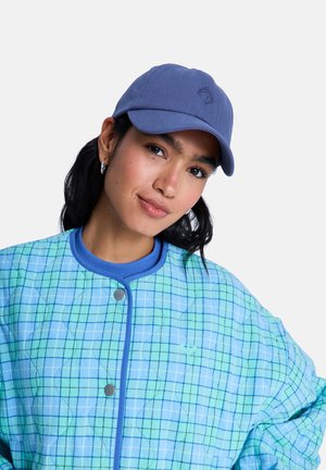 Prešívaná bunda s modro-zeleným károvaným vzorom, vybavená rebrovaným golierom a cvokmi na zapínanie. Mäkká, textúrovaná látka. Súčasťou je modrá baseballová čiapka.