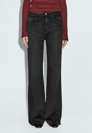 Czarne dżinsy o szerokich nogawkach, materiał dżinsowy, średni stan, pięć kieszeni, postrzępiony brzeg, w połączeniu z długim topem w czerwono-czarne paski.