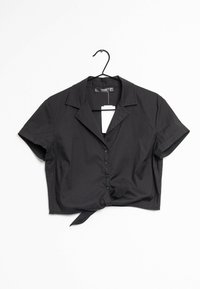 Blusa nera cropped con colletto, maniche corte, chiusura frontale con bottoni e dettaglio annodato all'orlo. Realizzata in tessuto liscio, presenta un design minimalista.