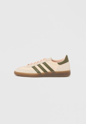 Flacher, beigefarbener Adidas Spezial Sneaker mit grünen Streifen, Gummisohle und "SPEZIAL" Schriftzug an der Seite, von der Außenseite gezeigt.