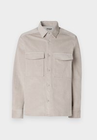 Camisa de pana de color beige claro con cierre de botones en la parte frontal, dos bolsillos en el pecho y cuello clásico. Presenta una tela texturizada y puños estándar.