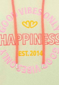 Un hoodie en tissu léger, avec un texte brodé multicolore : "GOOD VIBES ONLY" en rose et "HAPPINESS" en orange vif, avec des cordons en tresse rose.