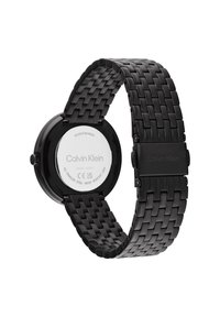 Reloj de acero inoxidable negro con una correa trenzada, caja redonda y un fondo pulido que presenta el nombre de la marca "Calvin Klein". Resistente al agua.