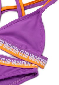Lila bikini felsőrész narancssárga és fehér "VACATION CLUB" pánttal. Simább anyagú, háromszög alakú mellek és állítható pántok jellemzik.