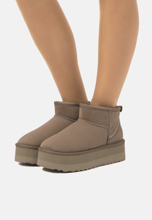 Botas marrones de altura hasta el tobillo con una superficie lisa y texturizada, que cuentan con una suela de plataforma y costuras en contraste a lo largo de las juntas.